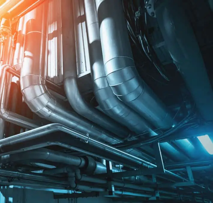 A complex network of industrial metal pipes designed for fluid equipment handling, with bright lighting highlighting their contours.