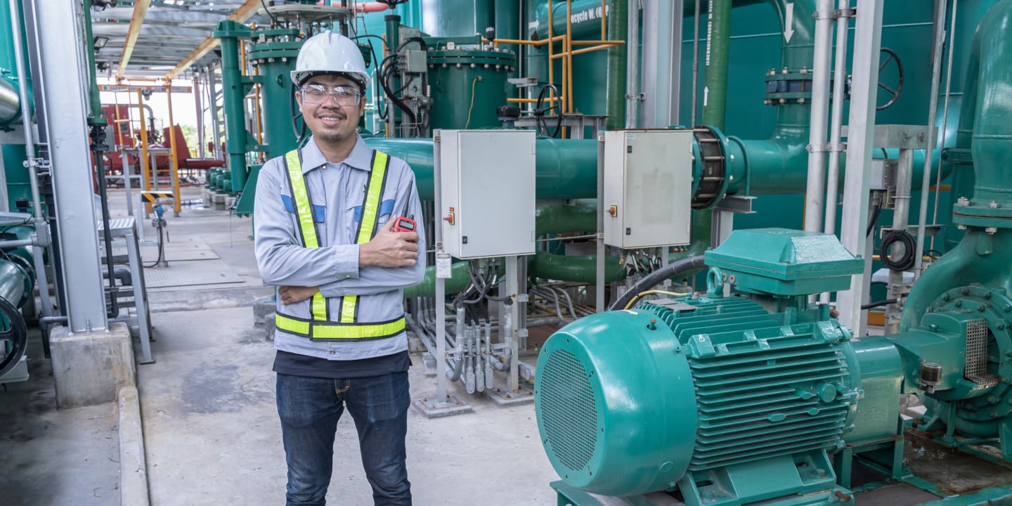 Asian male engineer working at factory with pipeline and pump.operator operation of oil and gas process at power plant, operator monitor production process, routine daily work ,water pipe.