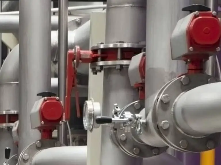 Industrial pipes with red valves and gauges, precision-configured using CPQ software for fluid handling equipment manufacturing.