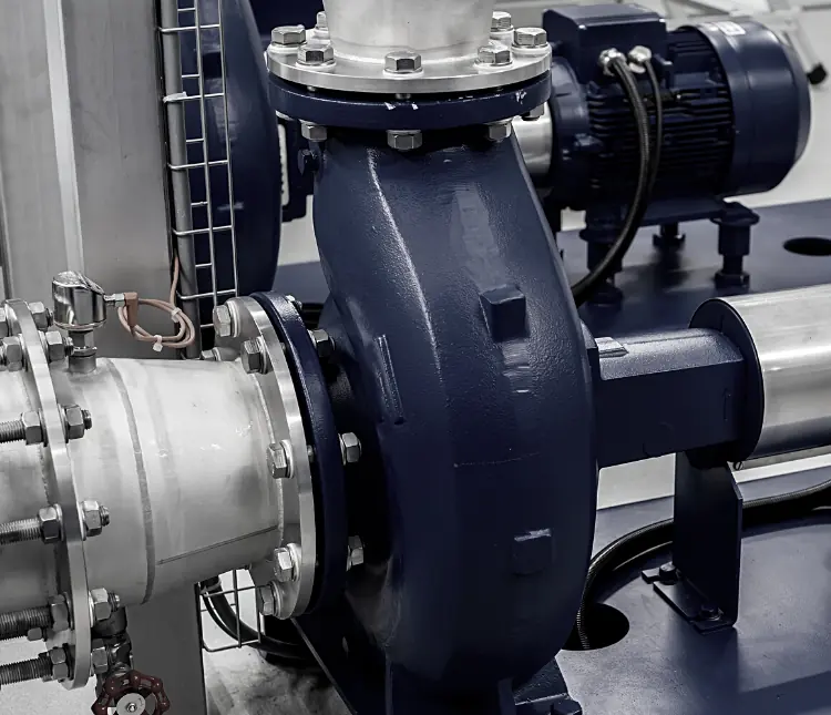 Close-up of an industrial pump and motor assembly with connected pipes, featuring metal fittings and bolts, in a factory setting optimized for CPQ software for pump manufacturers.