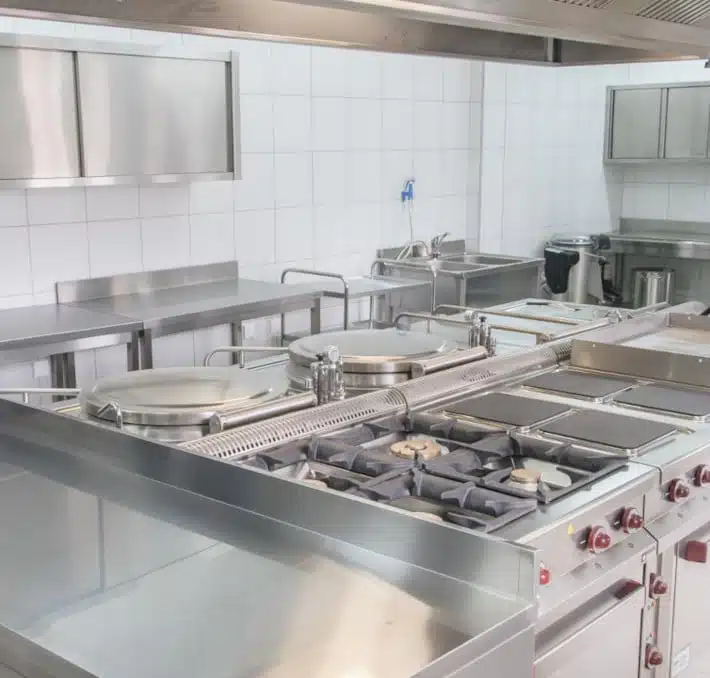 Discover a commercial kitchen designed with precision, featuring stainless steel appliances like stoves and ovens against pristine white tiled walls—a testament to exceptional foodservice design.