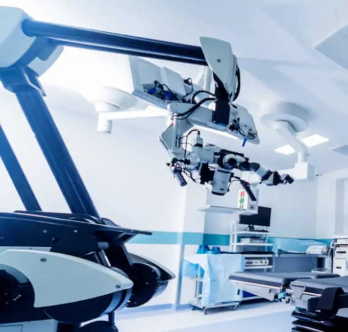 Robotic surgical equipment, expertly crafted by biomedical and clinical engineers, stands in a modern operating room with bright lighting and various medical devices.