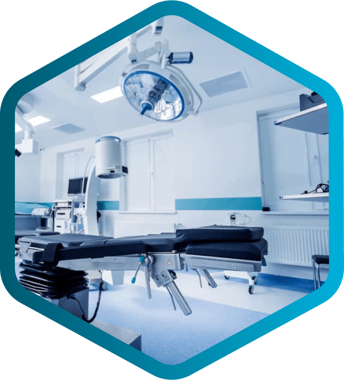 A modern, empty operating room with surgical lights, equipment, and an adjustable operating table—expertly maintained by Biomedical and Clinical Engineers—shown within a blue hexagonal border.