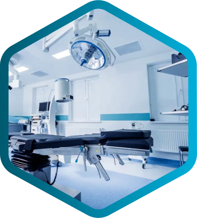 A modern, empty operating room with surgical lights, equipment, and an adjustable operating table—expertly maintained by Biomedical and Clinical Engineers—shown within a blue hexagonal border.