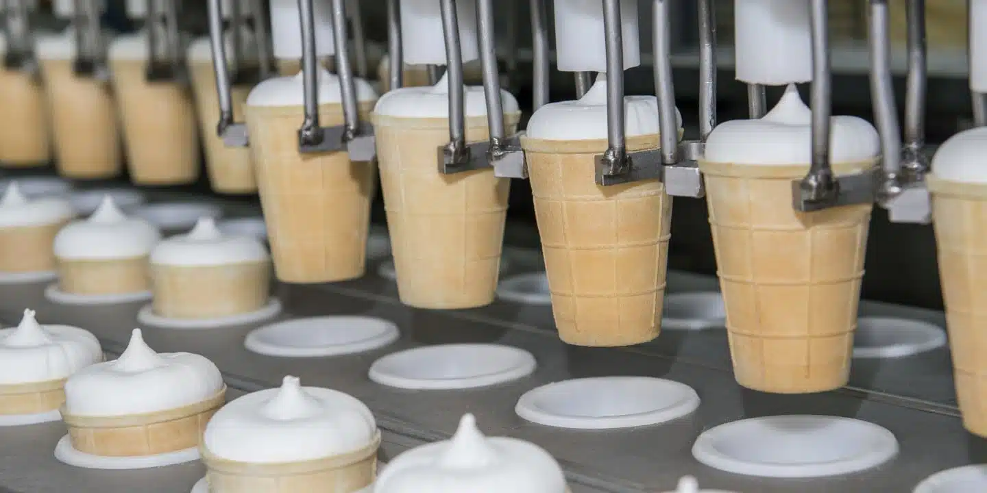 The automated production line efficiently fills ice cream cones with soft serve, showcasing the seamless integration of food & beverage PLM solutions.