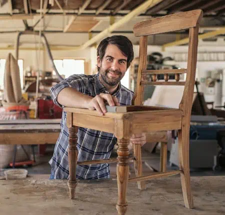 Man sanding a wooden chair