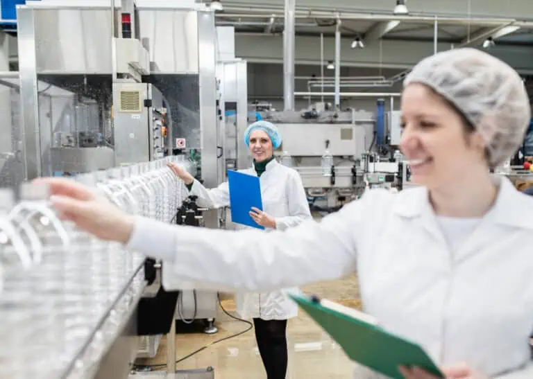 Woman checking bottle on assembly line