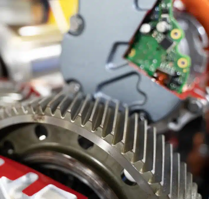 Close-up of mechanical gears and electronic circuit board, a testament to the craftsmanship involved in electrical equipment manufacturing, showcasing the intricate details of machinery and technology.