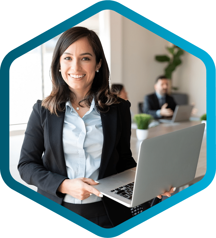 Woman in business attire holding a laptop and smiling, while two colleagues discuss HVAC equipment manufacturers CPQ solutions at a conference table in the background.