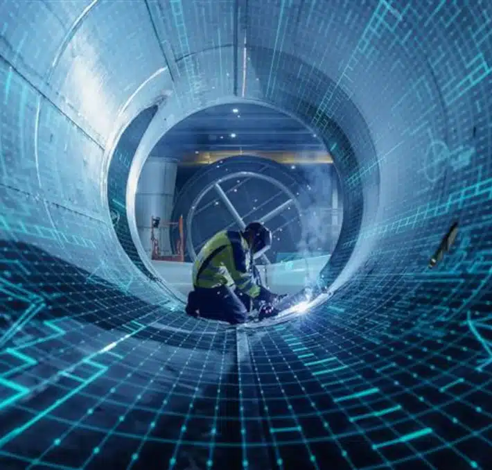 A worker in protective gear welds inside a large industrial pipe, overlaid with blue digital grid graphics, highlighting advanced technology and fluid management in modern manufacturing.
