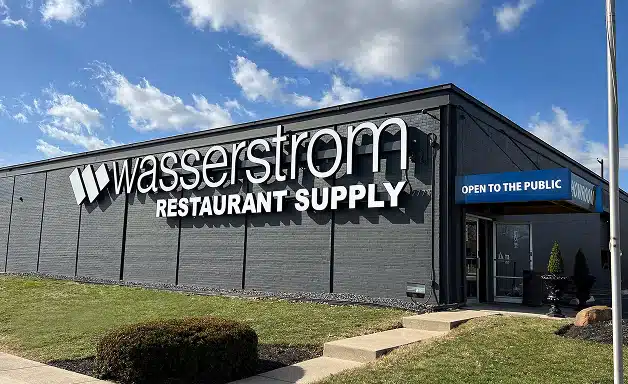 A gray building with Wasserstrom Restaurant Supply on the side and a blue awning reading Open to the Public above the entrance, featured in a recent Wasserstrom Case Study.