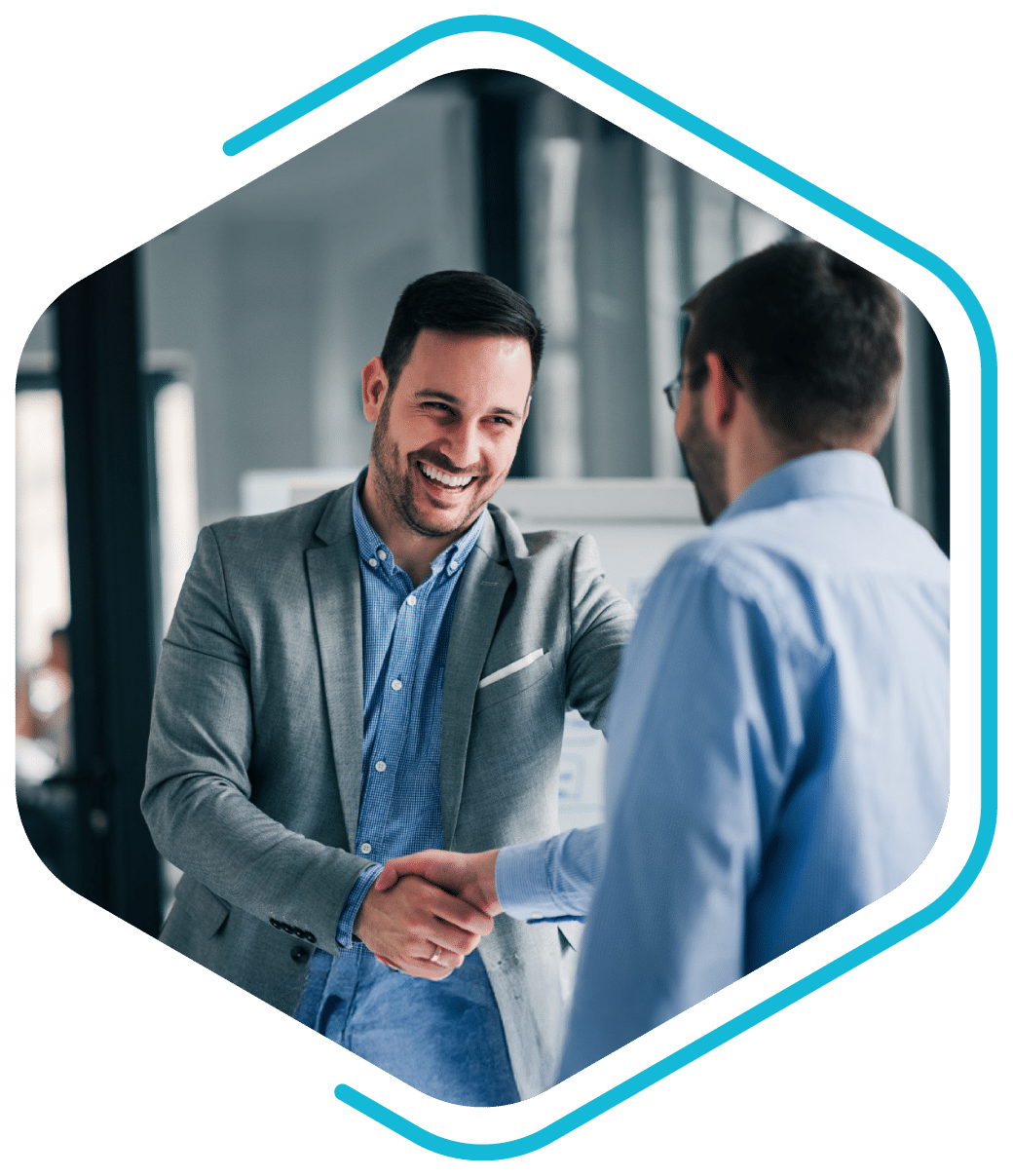 Two men wearing business attire shake hands and smile in an office setting, celebrating a new collaboration as Revalize partners.