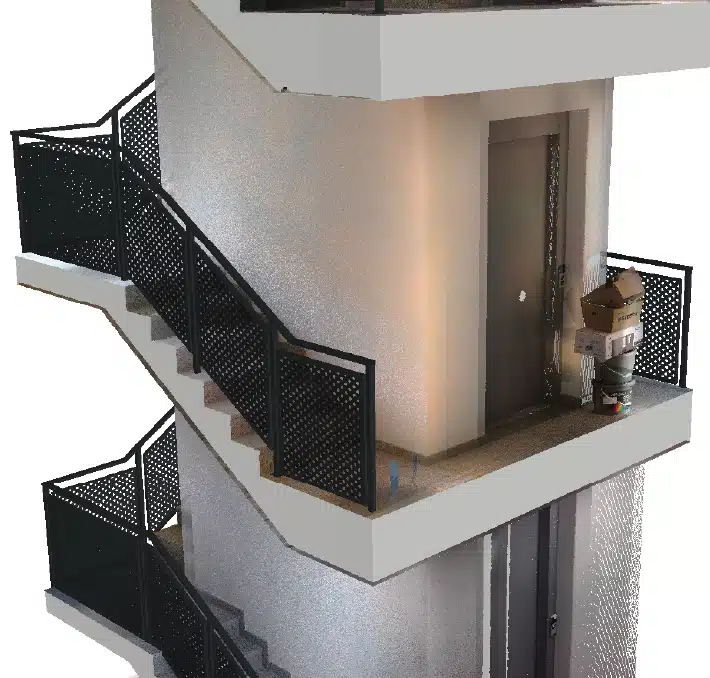 A stairwell with black metal construction railings leads to a landing where a closed door is visible; several cardboard boxes and a trash can are placed near the door.