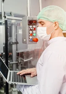 Man looking at laptop in front of food service equipment