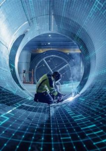 A worker in protective gear welds inside a large industrial pipe, overlaid with blue digital grid graphics, highlighting advanced technology and fluid management in modern manufacturing.